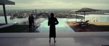 Movie still from “Mechanic: Resurrection” (2016), directed by Dennis Gansel – A man standing in front of a swimming pool looking out at a city; Extreme Wide shot, Over the shoulder angle