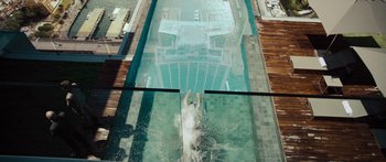 Movie still from “Mechanic: Resurrection” (2016), directed by Dennis Gansel – A man is swimming in a swimming pool; Extreme Wide shot, Overhead angle