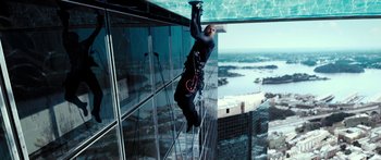 Movie still from “Mechanic: Resurrection” (2016), directed by Dennis Gansel – A man hanging from a rope on the side of a skyscraper; Wide shot, Low angle