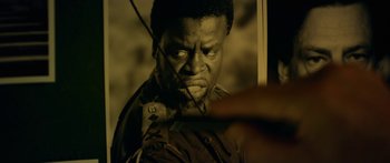 Movie still from “Mechanic: Resurrection” (2016), directed by Dennis Gansel – A man's face in a black - and - white photo; Extreme Close Up shot, Over the shoulder angle