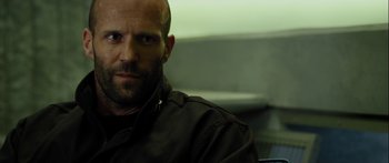 Movie still from “Mechanic: Resurrection” (2016), directed by Dennis Gansel – A man with a beard is sitting in a chair; Close Up shot, Low angle