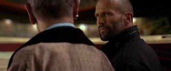 Movie still from “Mechanic: Resurrection” (2016), directed by Dennis Gansel – A man with a shaved head is looking at another man with a shaved head; Close Up shot, Over the shoulder angle