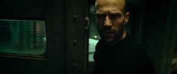 Movie still from “Mechanic: Resurrection” (2016), directed by Dennis Gansel – A man with a beard is standing in front of a door; Close Up shot, Low angle