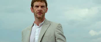 Movie still from “Mechanic: Resurrection” (2016), directed by Dennis Gansel – A person wearing a suit and tie; Close Up shot, Low angle