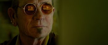 Movie still from “Mechanic: Resurrection” (2016), directed by Dennis Gansel – An older man wearing a pair of round sunglasses; Extreme Close Up shot, Low angle