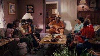 Movie still from “Meet the Browns” (2008), directed by Tyler Perry – A group of people sitting around a living room table; Wide shot, High angle