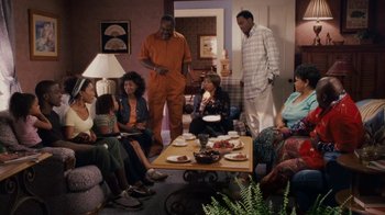 Movie still from “Meet the Browns” (2008), directed by Tyler Perry – A group of people sitting around a living room table; Wide shot, High angle