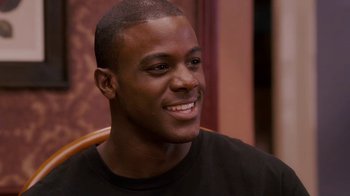Movie still from “Meet the Browns” (2008), directed by Tyler Perry – A person sitting in a chair smiling; Close Up shot, Over the shoulder angle