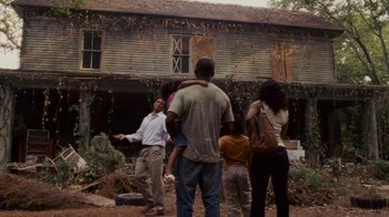 A group of people standing outside of an abandoned house