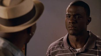 Movie still from “Meet the Browns” (2008), directed by Tyler Perry – A man standing next to another man wearing a hat; Close Up shot, Over the shoulder angle