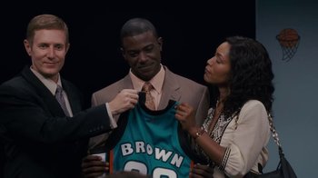 Movie still from “Meet the Browns” (2008), directed by Tyler Perry – A man and a woman are holding a basketball jersey; Medium shot, High angle