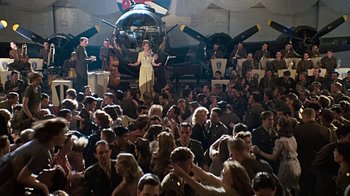 Movie still from “Memphis Belle” (1990), directed by Michael Caton-Jones – A group of people sitting in front of an airplane; Wide shot, High angle