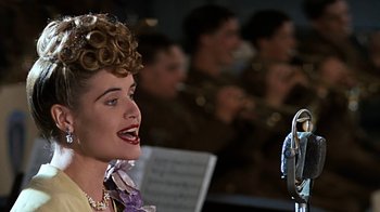 Movie still from “Memphis Belle” (1990), directed by Michael Caton-Jones – A woman in a purple dress is talking to a man in a military uniform; Close Up shot, Low angle