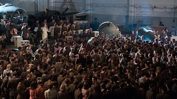 Movie still from “Memphis Belle” (1990), directed by Michael Caton-Jones – A crowd of people standing in a hangar; Extreme Wide shot, High angle