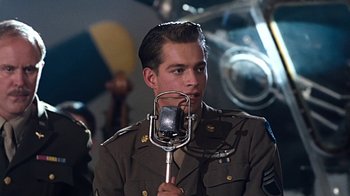 Movie still from “Memphis Belle” (1990), directed by Michael Caton-Jones – A man in a military uniform holding a microphone; Close Up shot, Low angle
