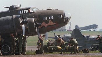 Movie still from “Memphis Belle” (1990), directed by Michael Caton-Jones – A group of men standing next to an airplane; Wide shot, Low angle