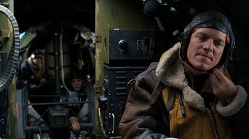 Movie still from “Memphis Belle” (1990), directed by Michael Caton-Jones – A man in a bomber jacket is in the back of an airplane; Close Up shot, Low angle
