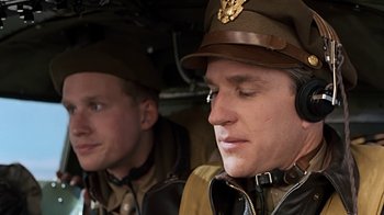 Movie still from “Memphis Belle” (1990), directed by Michael Caton-Jones – Two men in military uniforms are sitting in a helicopter; Close Up shot, Low angle