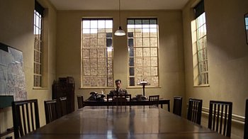 Movie still from “Memphis Belle” (1990), directed by Michael Caton-Jones – A man sitting at a table in front of two windows; Extreme Wide shot, Low angle