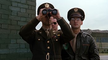 Movie still from “Memphis Belle” (1990), directed by Michael Caton-Jones – A man in a military uniform looking through binoculars; Medium shot, Low angle