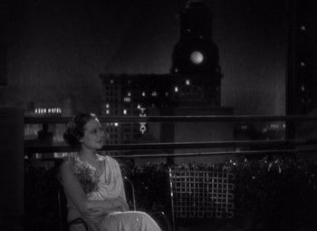 Movie still from “Merrily We Go to Hell” (1932), directed by Dorothy Arzner – A black and white photo of a woman sitting on a bench; Medium shot, High angle
