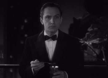 Movie still from “Merrily We Go to Hell” (1932), directed by Dorothy Arzner – A man in a suit and bow tie holding a drink; Close Up shot, High angle