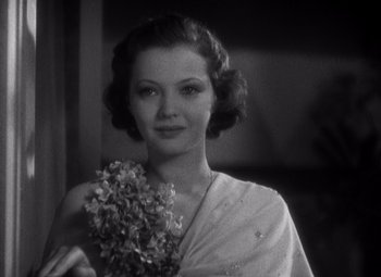 Movie still from “Merrily We Go to Hell” (1932), directed by Dorothy Arzner – A black - and - white photo of a woman holding flowers; Close Up shot, Low angle