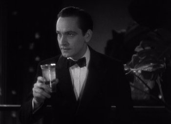 Movie still from “Merrily We Go to Hell” (1932), directed by Dorothy Arzner – A man in a tuxedo holding a glass of water; Close Up shot, High angle