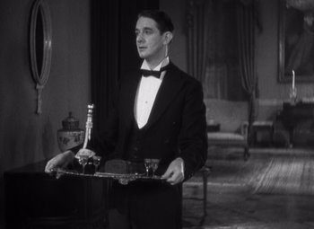 Movie still from “Merrily We Go to Hell” (1932), directed by Dorothy Arzner – A man in a tuxedo holding a tray of drinks; Medium shot, High angle
