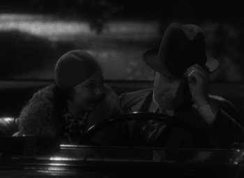 Movie still from “Merrily We Go to Hell” (1932), directed by Dorothy Arzner – A man and a woman sitting in the driver's seat of a car; Close Up shot, High angle
