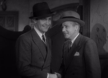 Movie still from “Merrily We Go to Hell” (1932), directed by Dorothy Arzner – Two men in suits and hats are shaking hands; Medium shot, High angle