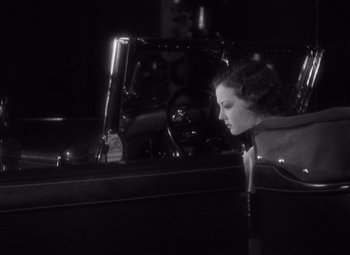 Movie still from “Merrily We Go to Hell” (1932), directed by Dorothy Arzner – A woman leaning up against the hood of a car; Medium shot, High angle