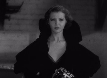 Movie still from “Merrily We Go to Hell” (1932), directed by Dorothy Arzner – A black and white photo of a woman holding a bag; Medium shot, Low angle