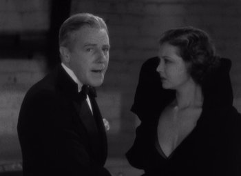 Movie still from “Merrily We Go to Hell” (1932), directed by Dorothy Arzner – An older man and a younger woman standing next to each other in front of a brick wall; Close Up shot, Low angle