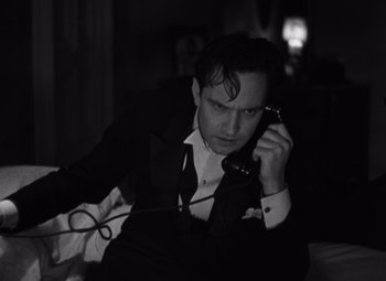 Movie still from “Merrily We Go to Hell” (1932), directed by Dorothy Arzner – A black and white photo of a man talking on a phone; Medium shot, High angle