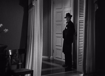 Movie still from “Merrily We Go to Hell” (1932), directed by Dorothy Arzner – A black and white photo of a man standing in a doorway; Wide shot, Low angle