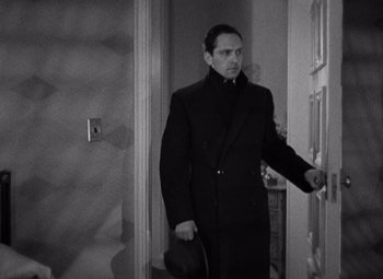 Movie still from “Merrily We Go to Hell” (1932), directed by Dorothy Arzner – A black and white photo of a man in a coat and hat; Medium shot, High angle