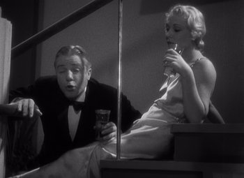 Movie still from “Merrily We Go to Hell” (1932), directed by Dorothy Arzner – A man and a woman sitting on a stair rail; Medium shot, Low angle