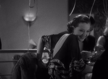 Movie still from “Merrily We Go to Hell” (1932), directed by Dorothy Arzner – An old photo of a woman sitting at a table; Medium shot, High angle