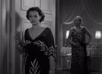 Movie still from “Merrily We Go to Hell” (1932), directed by Dorothy Arzner – A woman in a dress standing in front of a door; Medium shot, High angle
