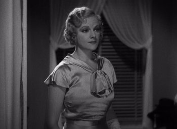 Movie still from “Merrily We Go to Hell” (1932), directed by Dorothy Arzner – A black - and - white photo of a woman standing in front of a window; Medium shot, High angle