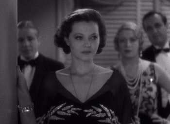 Movie still from “Merrily We Go to Hell” (1932), directed by Dorothy Arzner – A black and white photo of a woman in a black dress; Medium shot, Over the shoulder angle