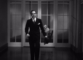 Movie still from “Merrily We Go to Hell” (1932), directed by Dorothy Arzner – A man in a suit and tie holding a monkey in his hand; Wide shot, Low angle