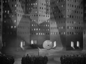 Movie still from “Metropolis” (1927), directed by Fritz Lang – A black and white photo of a group of people standing in front of a building; Extreme Wide shot, High angle
