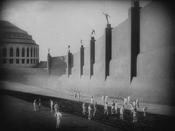 Movie still from “Metropolis” (1927), directed by Fritz Lang – A black and white photo of a group of people standing in front of a wall; Extreme Wide shot, Low angle