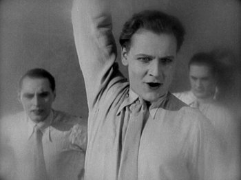 Movie still from “Metropolis” (1927), directed by Fritz Lang – A black and white photo of a man raising his hand; Medium shot, Low angle