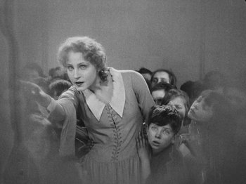 Movie still from “Metropolis” (1927), directed by Fritz Lang – An old black and white photo of a woman and a group of children; Medium shot, High angle