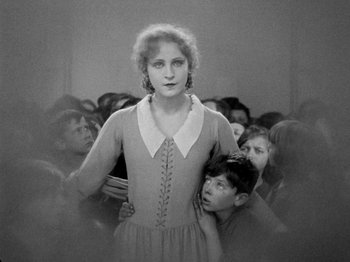 Movie still from “Metropolis” (1927), directed by Fritz Lang – An old black and white photo of a woman and a group of children; Medium shot, High angle
