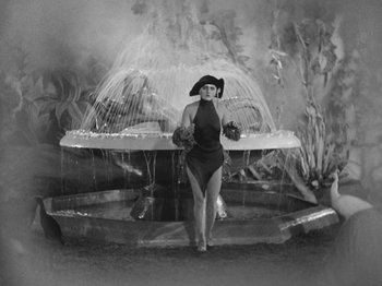 Movie still from “Metropolis” (1927), directed by Fritz Lang – A black and white photo of a woman standing in front of a fountain; Wide shot, High angle