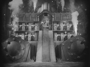 Movie still from “Metropolis” (1927), directed by Fritz Lang – A black - and - white photo of a building with steam coming out of it; Extreme Wide shot, High angle